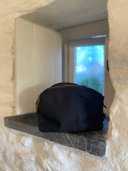 The Wild Isle Explorer Wash bag in on a stone ledge with a window in the background
