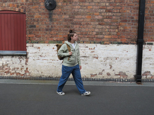 Model walking wearing the wild isle sand waxed canvas roll top back pack 