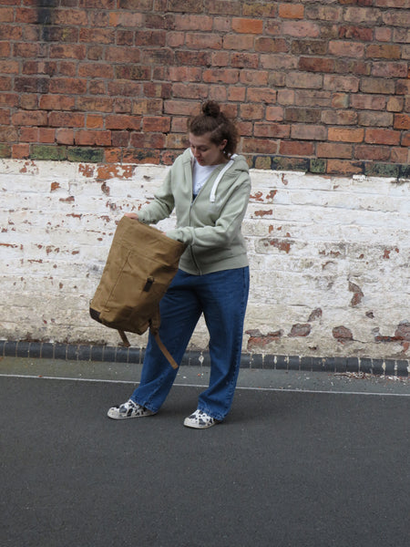 Model opening the wild isle waxed canvas roll top bag 