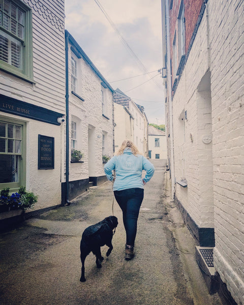 Sarah Pennell wearing the light blue wild isle hoodie walking broch the dog in a Padstow street