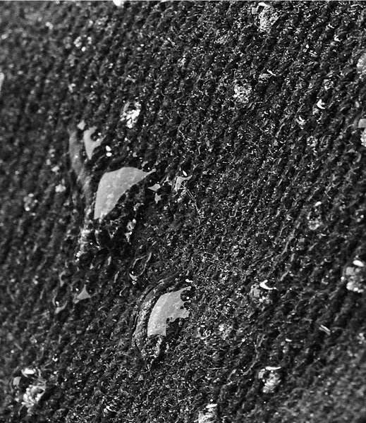 Close-up of a waxed canvas textured surface with water droplets showing water repellent