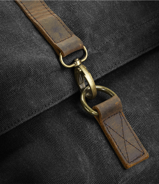 Close-up of the wild isle black waxed canvas bag with a brown leather strap and brass clasp