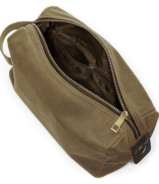 The wild isle waxed canvas wash bag/ toiletry bag with an open top zipper, showing a dark brown interior lining and a brass zipper pull, photographed on a white background.