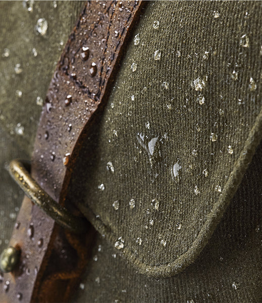 Close-up of the waxed canvas satchel with water droplets and a brass buckle.
