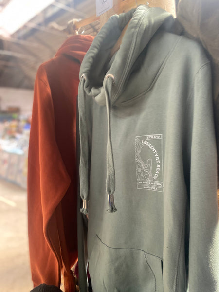 The wild isle forest Green hoodie with a personalised logo on a hanger in a store setting