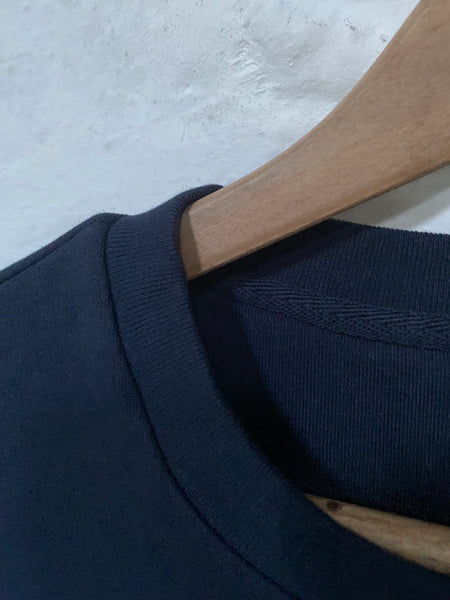 A close up of the Wild Isle Terry T-shirt hanging on a hanger against a white wash wall.