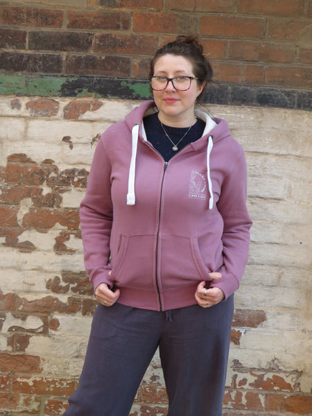 Person wearing a Wild Isle Trail Zip Up  Hoodie with a brick wall background.