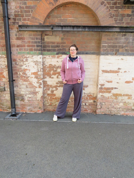 Person standing in front of a brick wall wearing a Wild Isle Trail Zip Up Hoodie 