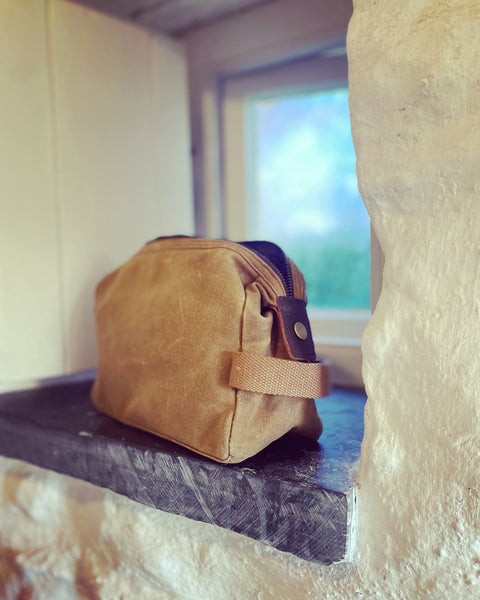 Wild Isle Wash Bag in sand on a bathroom shelf 