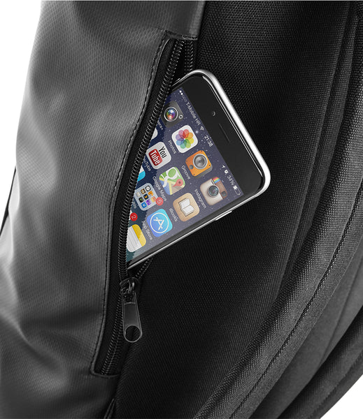Close-up of a black backpack pocket with a smartphone partially tucked inside, showing the phone screen and the black fabric texture of the bag.