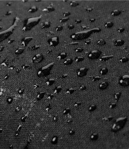 Close-up of the waxed canvas surface covered with water droplets, showing a waterproof or water-repellent finish.
