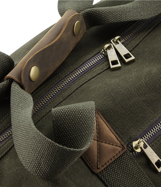 Close-up of the moss green waxed canvas wild isle cabin bag with leather accents and zippers.