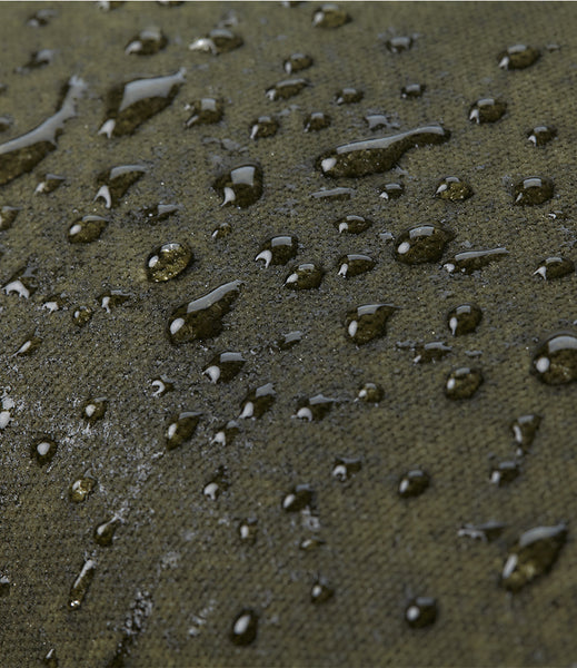 Close-up of the moss green waxed canvas  fabric covered with water droplets, showing a waterproof or water-repellent finish.