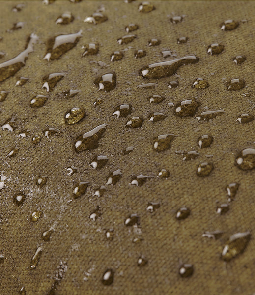 Close-up of the wild isle waxed canvas fabric surface covered with water droplets, showing a waterproof or water-repellent finish.