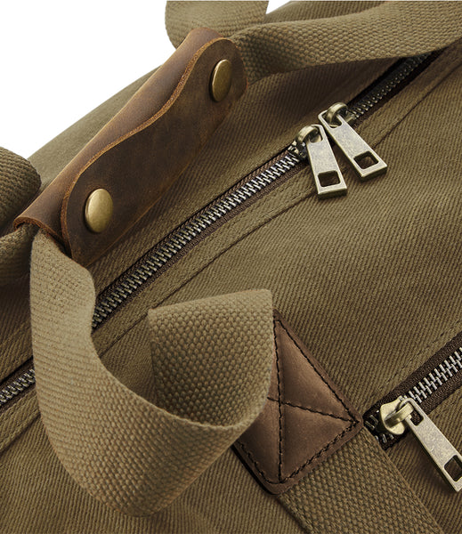 Close-up of the wild isle waxed canvas sand cabin bag showing the carry handle and brass zips 
